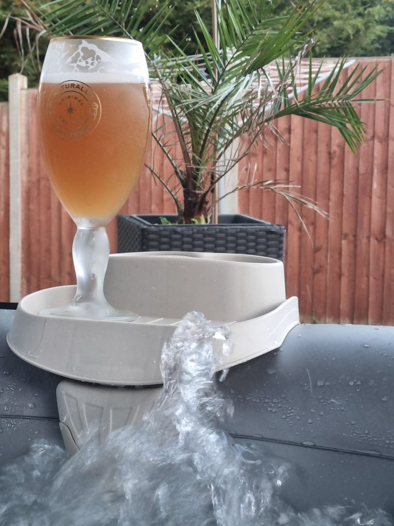 A drink resting on the edge of a hot tub in the evening