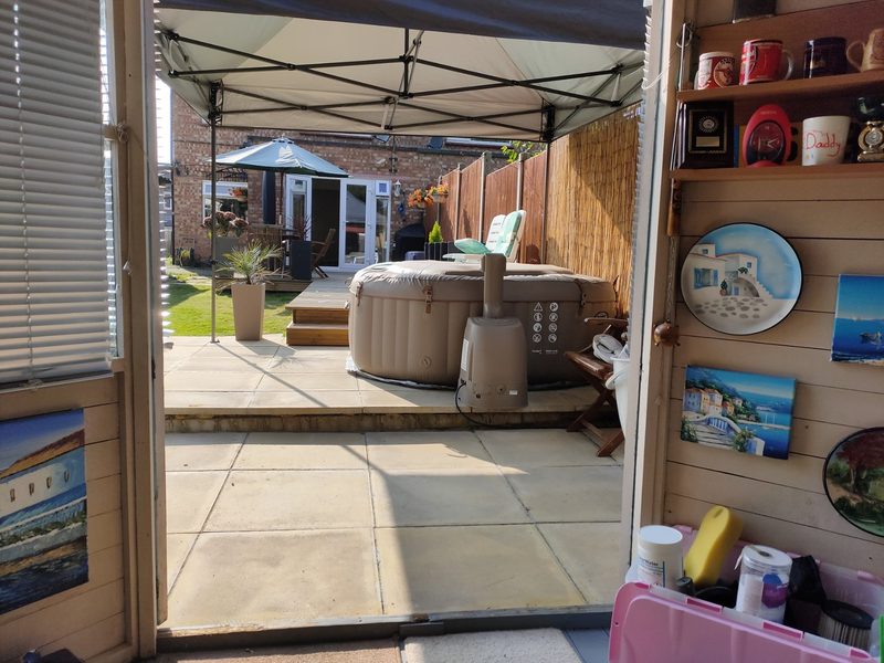 A hot tub under a gazebo in a back garden