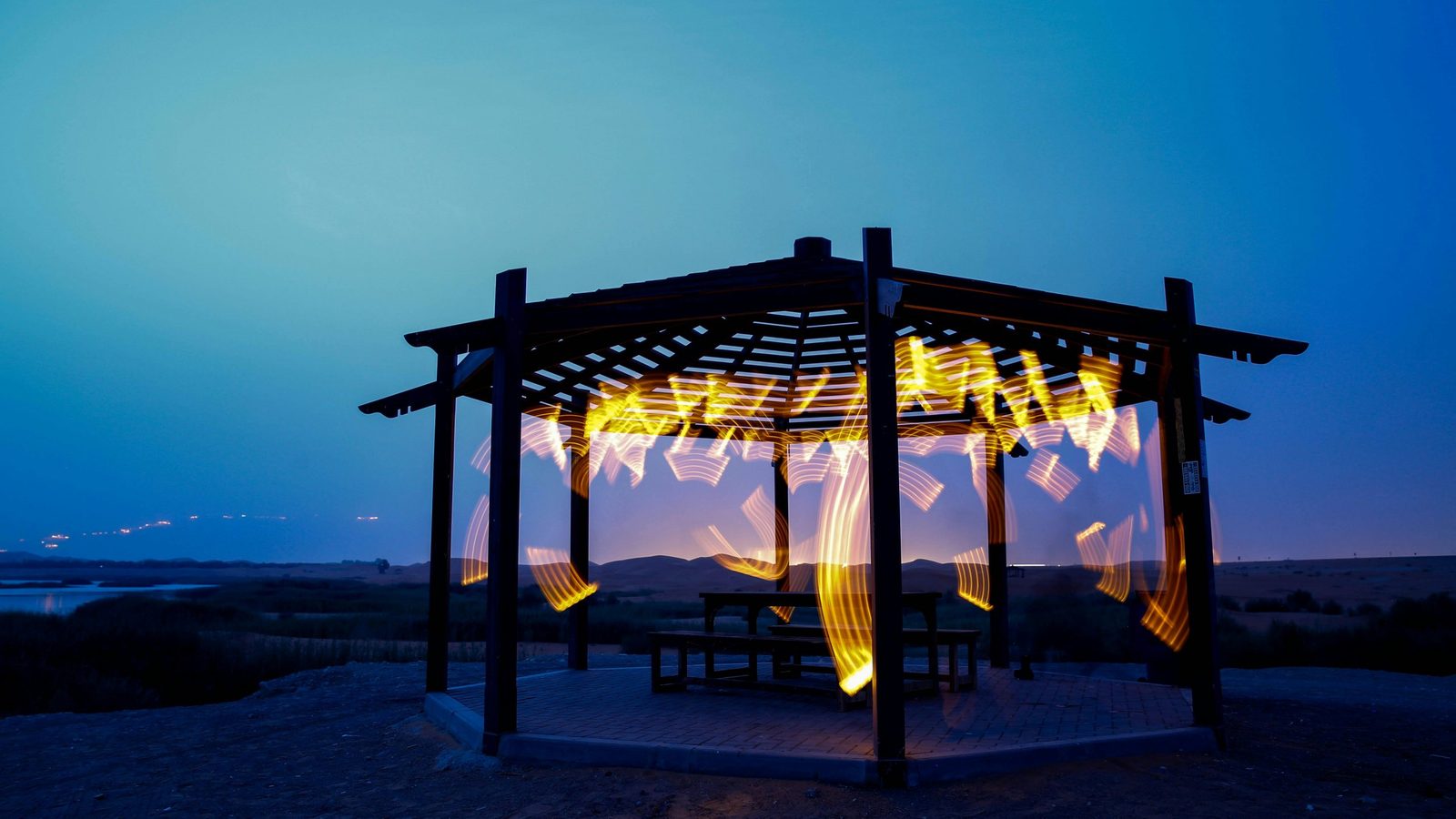 A lit pergola in a garden at dusk