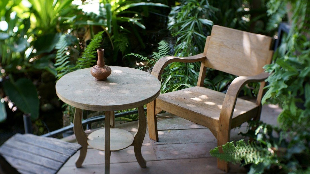 A garden table and chair surrounded by planting