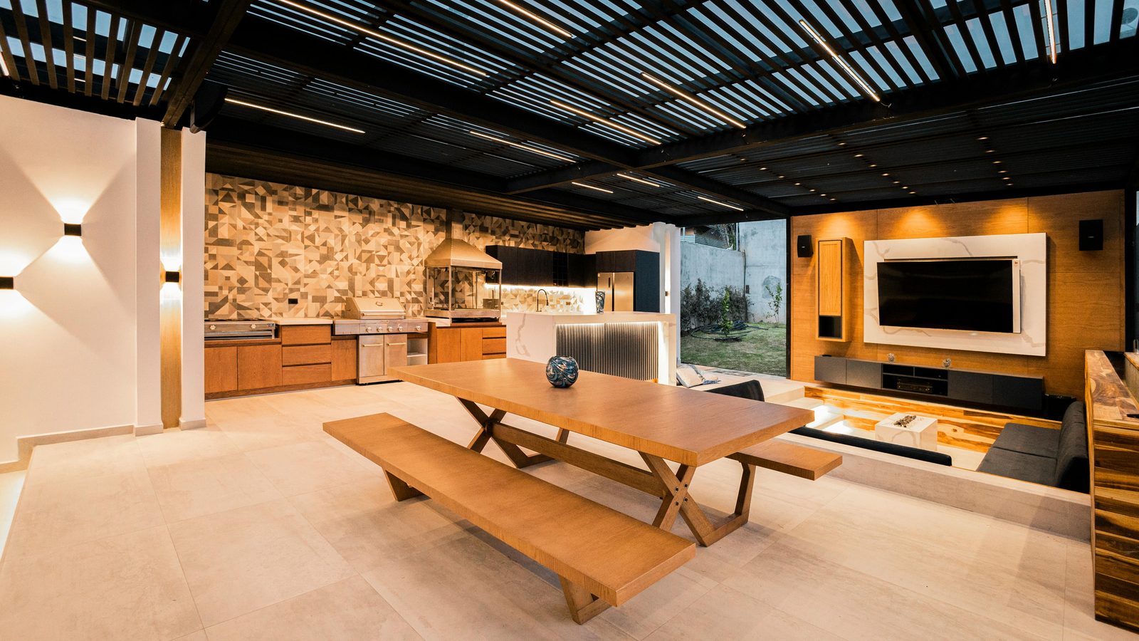 A modern covered outdoor room with a long dining table