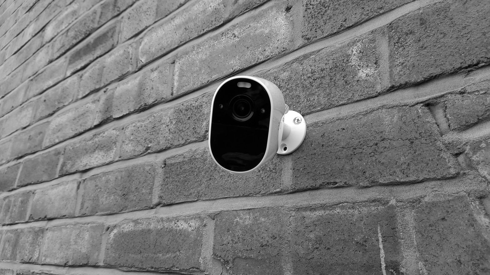 A wireless security camera mounted on a brick wall